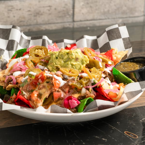 Loaded nachos with beef, guacamole, jalapeños, pickled onions, and salsa verde from R Bar.