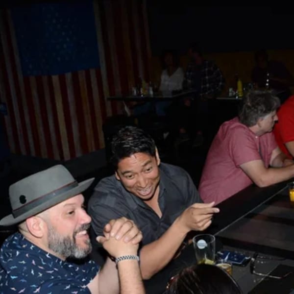 Patrons enjoying drinks and conversation at R Bar, with an American flag in the background.