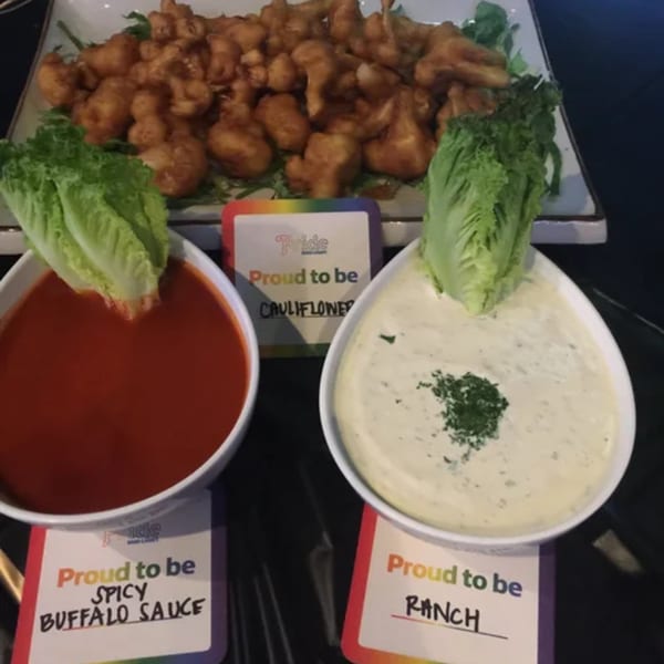 Fried cauliflower bites with spicy buffalo sauce and ranch dressing, garnished with lettuce.