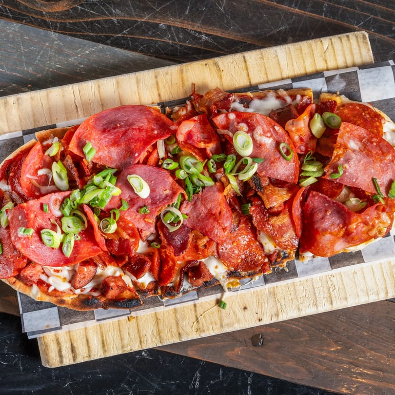 R Bar's flatbread pizza, topped with pepperoni, salami, bacon, cheese, and green onions.