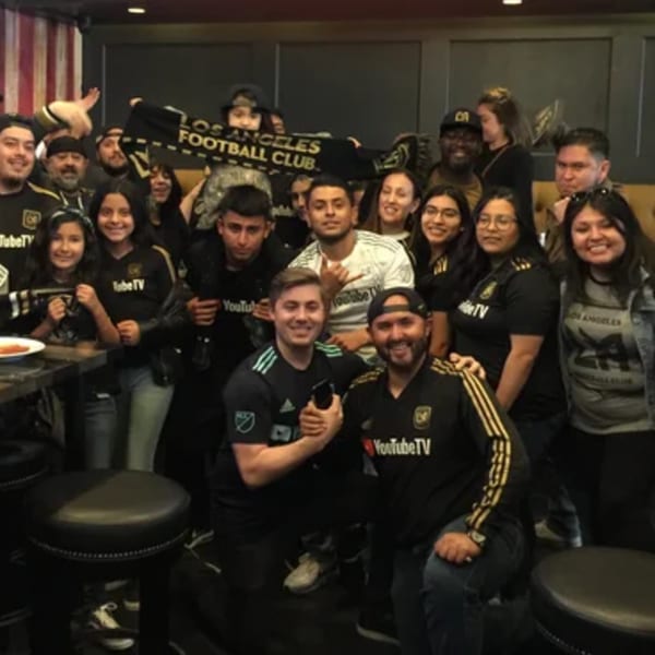 A large group of people, many wearing LAFC gear, posing together inside R Bar.