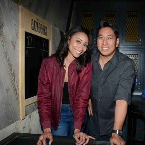 Smiling man and woman posing together at R Bar, with a chalkboard sign behind them.