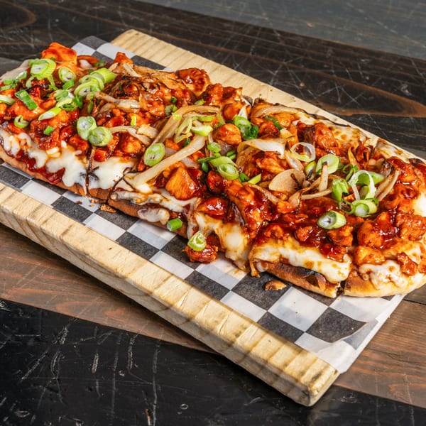 R Bar's BBQ chicken flatbread pizza, topped with melted cheese, caramelized onions, and green onions.
