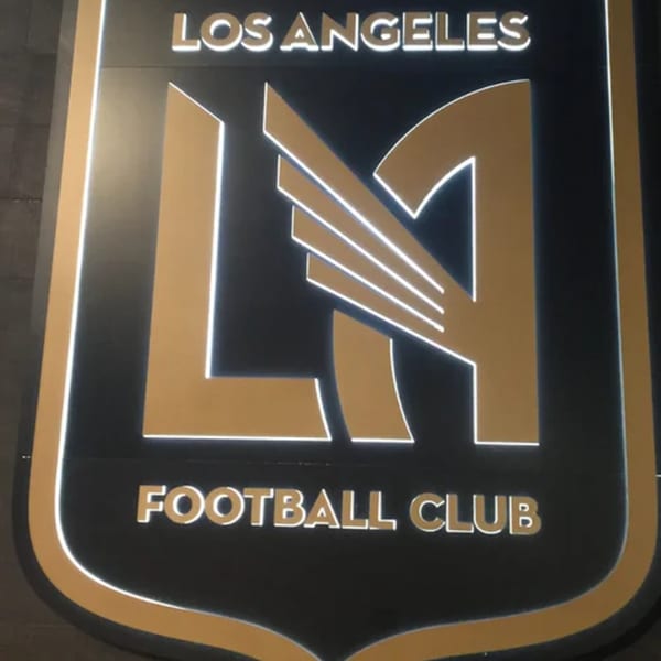 A black and gold Los Angeles Football Club logo sign with glowing white edges.